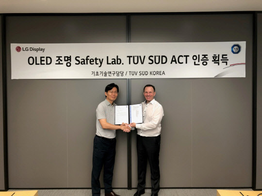 LG디스플레이는 독일 시험인증기관 'TUV SUD'에게 OLED조명 안전 규격 시험을 자체적으로 수행할 수 있는 자격을 인증을 받았다고 3일 밝혔다. 이날 서울 마곡동 LG사이언스파크에서 열린 인증서 전달식에서 배종욱 LG디스플레이 기초기술연구담당(왼쪽)과 예쎄폴커 TUV SUD 코리아 제품인증사업부 총괄전무가 기념촬영을 하고 있다. <LG디스플레이 제공>